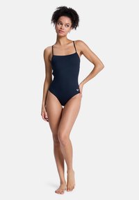 Černé jednodílné plavky s tenkými ramínky, čtvercovým výstřihem a přiléhavým střihem. Vyrobené z hladkého, pružného materiálu. Jemný detail s logem.