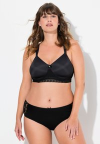 Set di lingerie nero composto da un reggiseno liscio in satin con bordi in pizzo e un fiocco, abbinato a mutandine nere seamless con dettagli in pizzo.