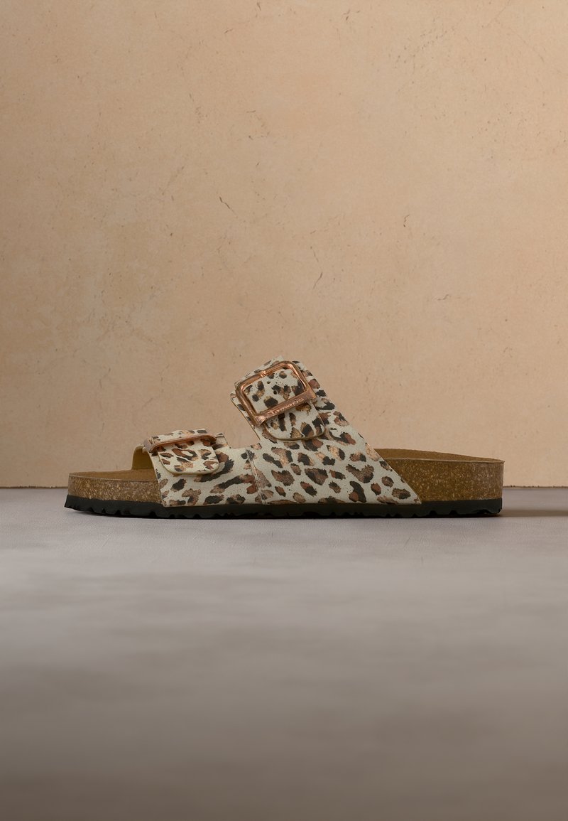 Sandales avec une semelle en liège et deux brides réglables avec un motif léopard sur un fond neutre.