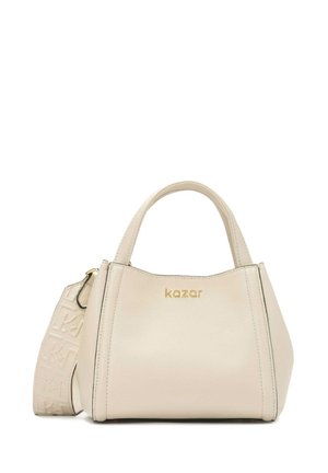 Sac à main en cuir beige au design structuré, avec de courtes poignées supérieures et une bandoulière amovible, comportant des accents en relief et un logo doré.