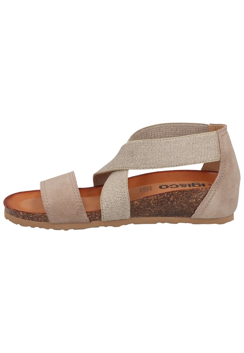 Beige mockasin sandal med korsade elastiska remmar, korkfotbädd och texturerad gummisula. Låg kildesign med en minimalistisk estetik.