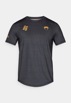 Črna atletska majica s kratkimi rokavi z geometrijskim vzorcem, z oranžnimi logotipi na sprednjem delu in rokavu, izdelana iz gladkega blaga.