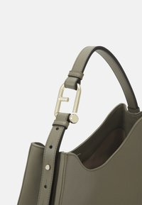 Sac à main en cuir vert avec une texture lisse, doté d'une fermeture en métal doré et d'une bandoulière réglable avec plusieurs trous.
