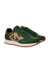 Sneaker verde in suede e rete con un'accennatura beige ai lati, logo nero e suola in gomma marrone. Presenta lacci piatti e una linguetta imbottita.