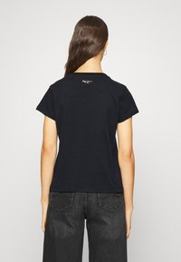 Svart bomull T-shirt med korta ärmar, med en rundad halsringning. Litet logotyp i guld på den övre delen av ryggen. Mjuk textur.