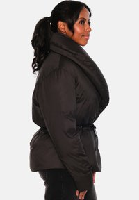 Svart puffjakke med stor, brettet krage, innsvingt midje og vide ermer. Kjennetegnes av en glatt, skinnende tekstur og en avslappet passform.