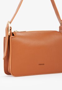 Borsa a tracolla in pelle color arancio bruciato con finitura testurizzata, dotata di cerniera e dettagli in oro, e una tracolla regolabile.