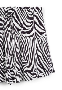 Pantaloni corti a strisce zebrate in bianco e nero con una fascia elastica in vita, realizzati in un tessuto leggero e con un orlo che curva dolcemente.