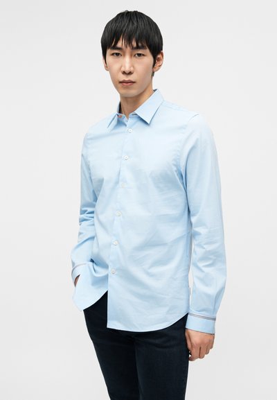 Šviesiai mėlyna marškiniai su sagutėmis, pagaminti iš lygaus audinio, turintys klasikinius apykaklę, ilgomis rankovėmis ir kontrastingomis apdailos detalėmis rankogaliuose.