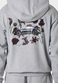 Grauer Hoodie mit einer Illustration eines Vintage-Blau-Sportwagens, umgeben von dunkelroten und violetten Blumen auf der Rückseite.