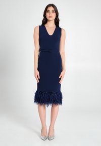 Marineblaues, enganliegendes Kleid mit V-Ausschnitt, tailliertem Gürtel und Federsaum. Glattes Material mit strukturiertem Fransensaum am Boden.