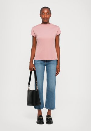 Light pink short-sleeve top, slightly high-neck design, paired with light blue flared jeans. Holding a black bucket bag, wearing black loafers.