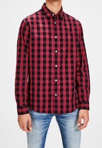 Red and black checkered button-up shirt with long sleeves, made from cotton, featuring a structured collar and white buttons.