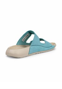 Sandale turquoise avec une tige en daim et une semelle en caoutchouc beige. Dispose d'un dos ouvert et de découpes latérales, d'un design plat et d'accents cousus.