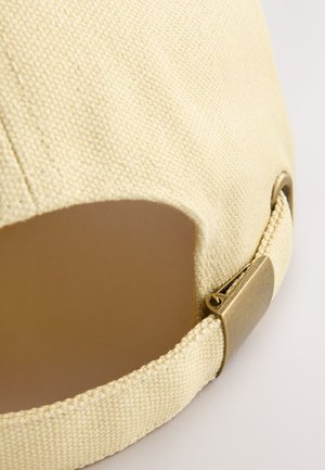 Cappellino beige chiaro realizzato in tessuto strutturato con visiera curva. Presenta una fibbia metallica e un'apertura sul retro per la regolazione della misura.