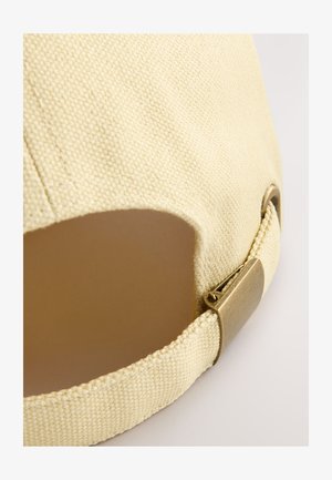 Licht beige pet gemaakt van gestructureerde stof met een gebogen klep. Voorzien van een metalen gesp en een uitsparing aan de achterkant voor verstelbare maatvoering.