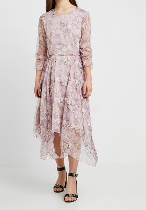 Robe florale lilas avec des manches longues transparentes, un col rond et un ourlet asymétrique. Le tissu présente de délicats motifs de fleurs.