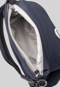 Granatowa torba materiałowa z zamkiem błyskawicznym. Podszewka wewnętrzna z powtarzającym się wzorem logo. Wytrzymałe materiały o gładkiej fakturze.