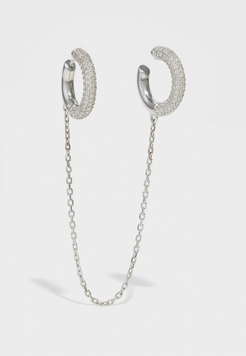 Orecchini a cerchio in argento con una superficie texturizzata e scintillante. Collegati da una delicata catena, hanno un design curvo con una finitura lucida.