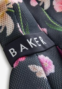 Stoffen met bloemenpatroon en een gestructureerd oppervlak in zwart, met een geweven label met "BAKER" in witte letters.
