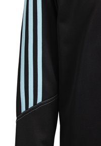 Maillot de sport noir avec un design de trois rayures bleues sur l'épaule et des détails de couture contrastants le long des coutures.