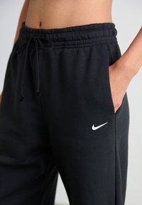 Schwarze Baumwoll-Sweatpants mit elastischem Bund und Kordelzug. Enthält ein weißes Nike-Logo auf der linken Seite, entworfen für Komfort.