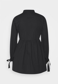 Svart långärmad blus med gathered midja, krage och snörningar på ärmarna, tillverkad av ett mjukt och slätt tyg.