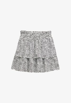 Tiered skirt in white fabric with black dot pattern. Features an elastic waistband and ruffled layers for volume and texture.