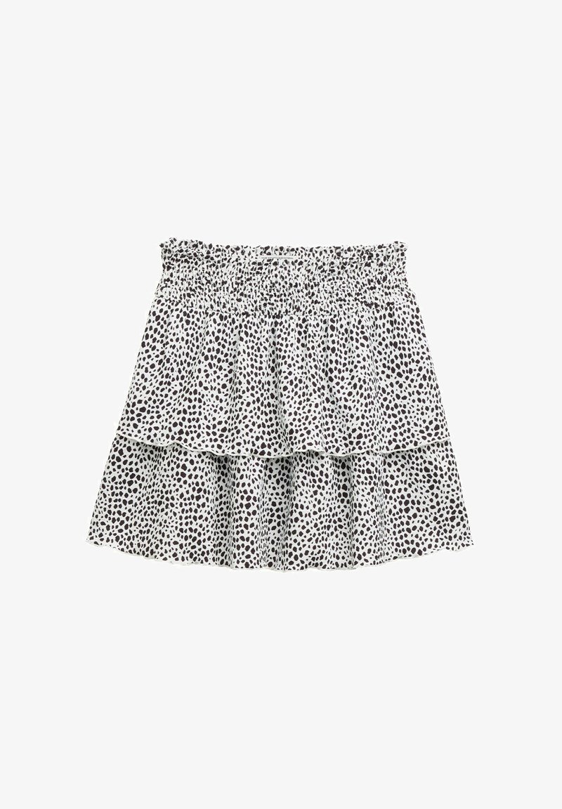 Fehér anyagú, fekete pöttyös, réteges szoknya. Rugalmas derékkal és fodros rétegekkel rendelkezik, amelyek térfogatot és textúrát adnak.