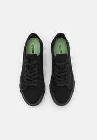 Black canvas sneakers featuring a round toe, textured fabric, black laces, and a green insole with "YOURTURN" printed on it.