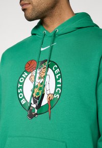 Πράσινο φούτερ με κουκούλα από βαμβακερό μείγμα με το λογότυπο των Boston Celtics που απεικονίζει έναν λεμπρέχον που κρατά μια μπάλα μπασκετ, με ρυθμιζόμενη κουκούλα με κορδόνι και μπροστινή τσέπη.