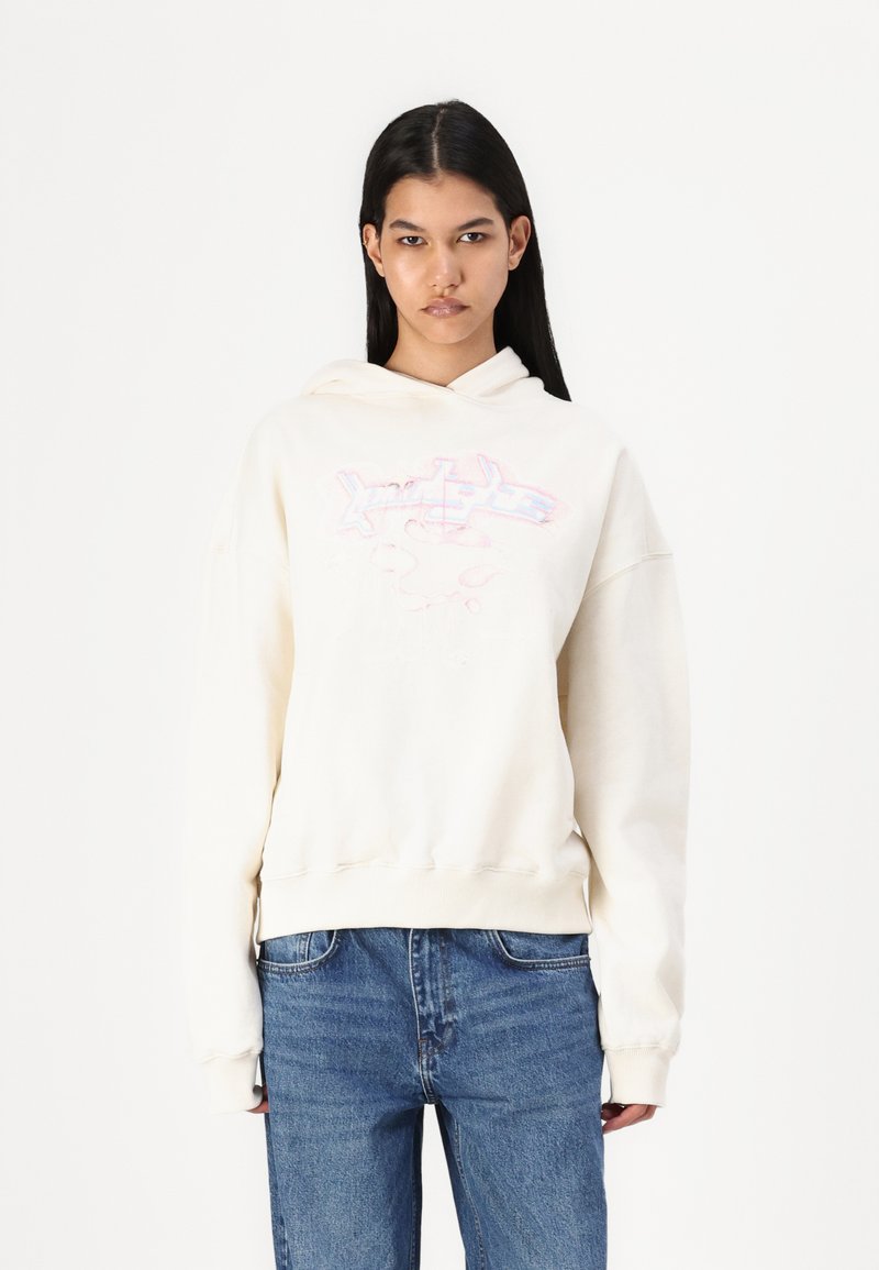 Cream-colored hooded sweatshirt with a loose fit, featuring a graphic design in pink and blue on the front, ribbed cuffs, and hem.