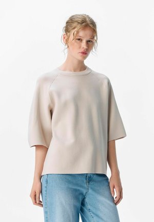 Lichtbeige T-shirt met korte mouwen van een zachte, gestructureerde stof, voorzien van een ronde halslijn en een ontspannen pasvorm. Draagt bij lichte spijkerbroeken.