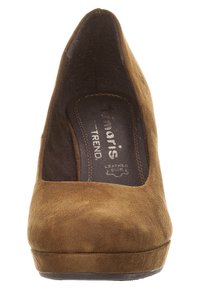 Zapato de tacón alto de ante marrón con punta afilada y parte superior texturizada, que cuenta con una plantilla acolchada y una suela lisa.