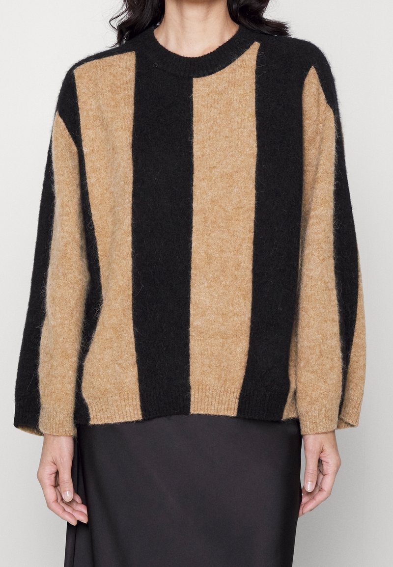 Beige und schwarz gestreifter Pullover aus weichem, strukturiertem Stoff. Hat einen runden Ausschnitt und weite Ärmel, mit einer lockeren Passform.