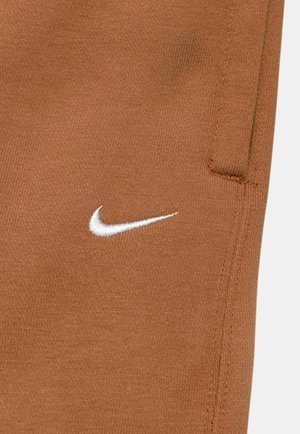 Brune Nike sweatpants lavet af materiale med en glat tekstur. Har et hvidt logo og lommer, samt pæne stikninger på siderne.