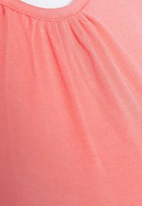 Korálová látka se skládacím výstřihem, hladkým povrchem a jemným leskem. Lehký a elastický materiál pro pohodlí.