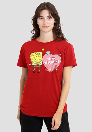 Red short-sleeve T-shirt featuring a cartoon character and a heart-shaped graphic with the text "BE MY VALENTINE." Soft fabric, casual fit.