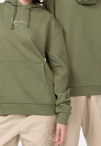 Olivgrön huvtröja i bomullsblandning, med en framficka och ribbade muddkanter, med broderad logotypdetalj på bröstet.