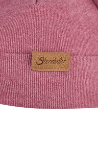 Knitted beanie in light pink with a ribbed texture. Features a brown leather tag stitched on the cuff with "Sternstaler" embossed.
