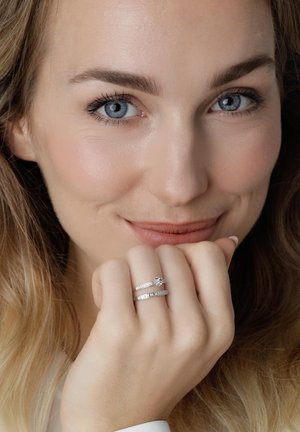 Witgouden ringen met een centrale steen en pavé-accenten, getoond op een hand. Vloeiende textuur, gepolijste afwerking en stralende glans.