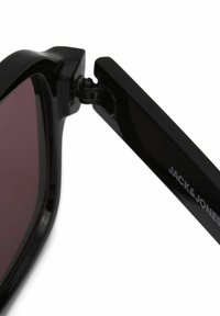 Schwarze Sonnenbrille mit einem glänzenden Rahmen, lila getönten Gläsern und einem Metall-Scharnier. Der Markenname "JACK & JONES" ist auf dem Bügel aufgedruckt.