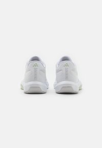 Scarpe sportive bianche con tessuto a rete e dettagli verdi. Presentano un tallone arrotondato e la scritta "TRAINING" sul retro. Suola in gomma per una migliore aderenza.