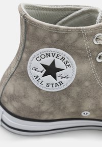 Gray suede high-top sneaker with white rubber sole, featuring a black star logo patch and contrasting stitching details.