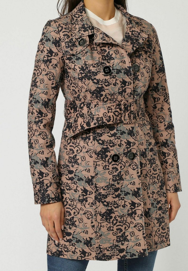 Trench coat con estampado floral en rosa pálido y negro con detalles en azul, hecho de tejido ligero. Cuenta con botones de doble botonadura y un cinturón.