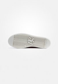 Semelle de chaussure avec une base en caoutchouc blanc, présentant un motif en chevrons et un détail de logo, conçue pour l'adhérence et la durabilité. Forme plate et arrondie.