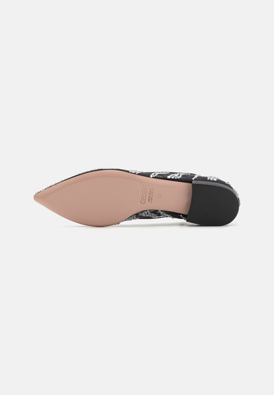 Pantofii decorativi negri și albi, cu vârful ascuțit, ornamentați cu paiete. partea inferioară netedă cu o talpă călduță de culoare maronie și un accent negru la toc.