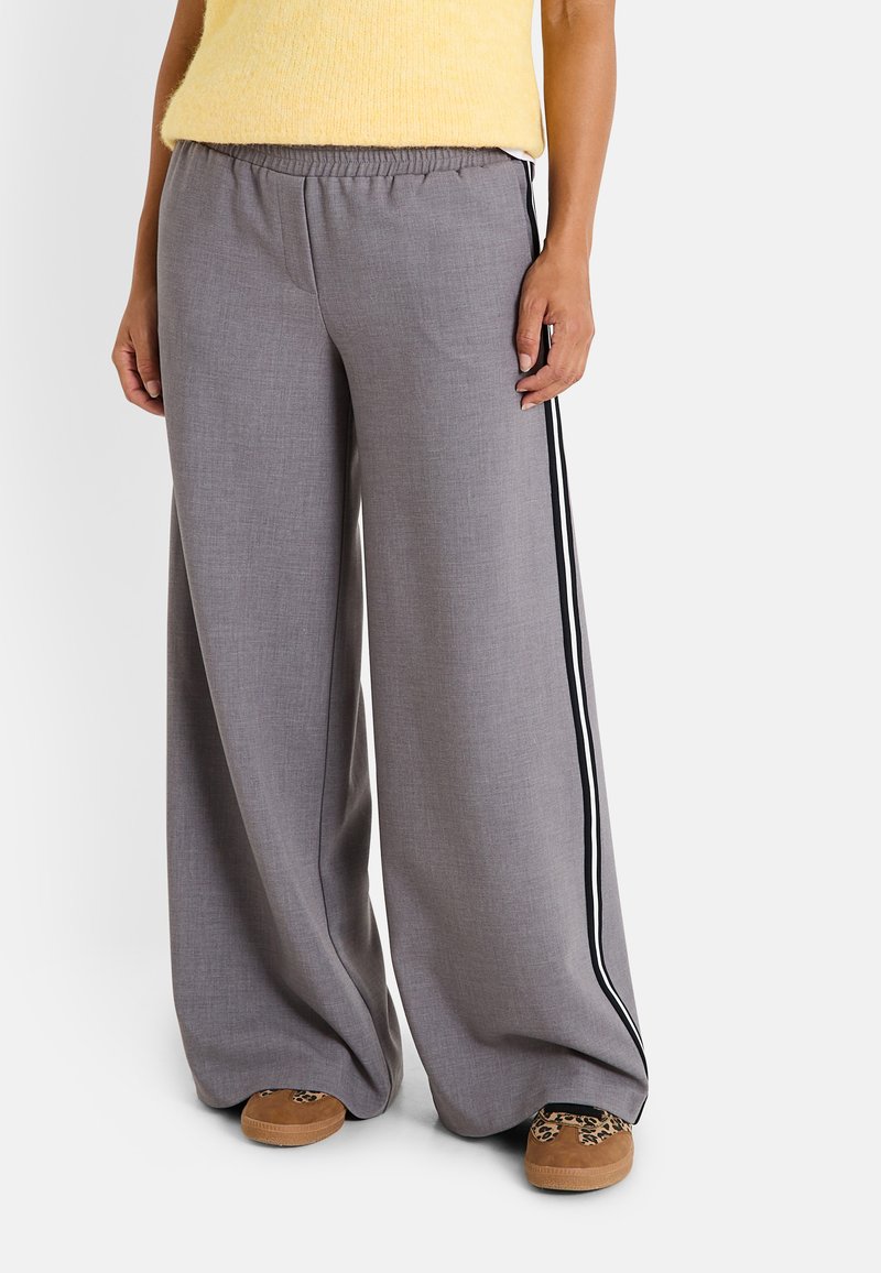 Pantalones de pernera ancha en gris con una cinturilla elástica, que presentan franjas laterales negras. La tela tiene una textura suave con un brillo sutil.