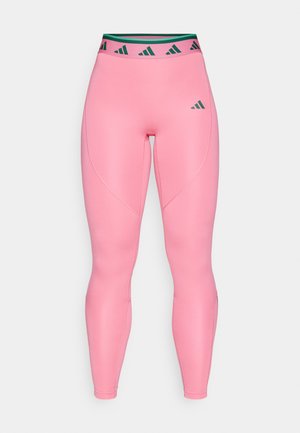Roze tajice napravljene od glatkog, rastezljivog materijala. Imaju pojas s crno-zelenim uzorkom i suptilan logo na butu.