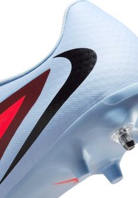 Scarpe da calcio azzurro chiaro con tomaia texturizzata, caratterizzate da uno swoosh nero e dettagli rossi. Tacchetti trasparenti sulla suola per una migliore trazione.